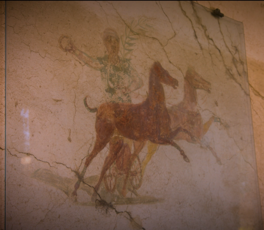 A man on a chariot drawn by two horses going left to right