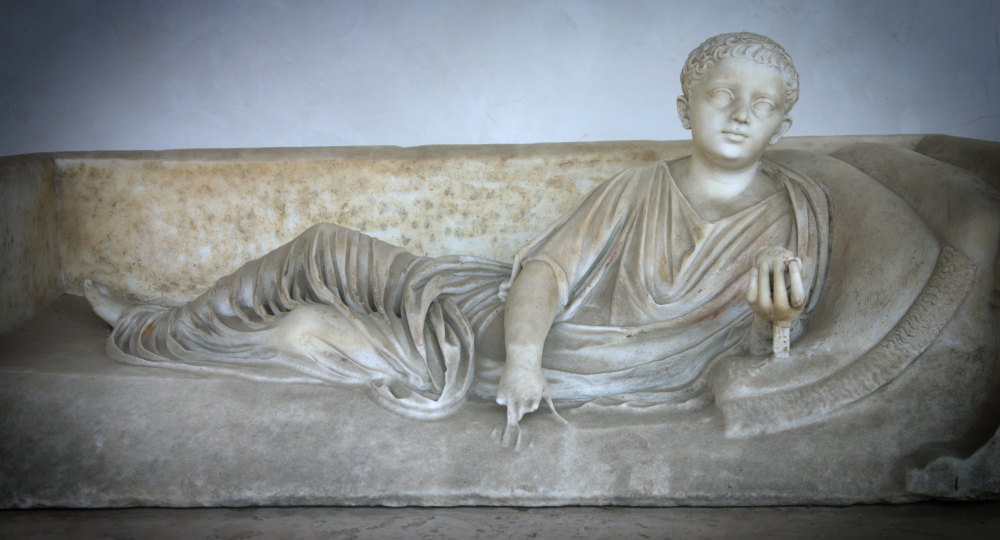 Marble statue of a young man in a toga holding a fruit